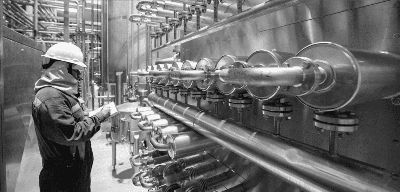Maintenance technician inspecting industrial piping system in a processing plant – demonstrating planning and scheduling in maintenance operations on reliabilityacademy.com.