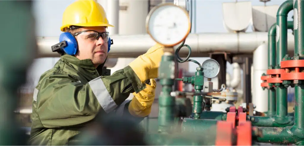 Maintenance engineer checking pressure gauge at industrial plant to ensure equipment reliability