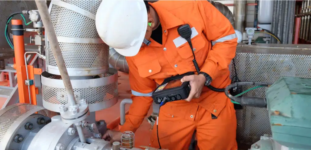 Maintenance technician using handheld diagnostic tool to inspect rotating equipment in processing facility
