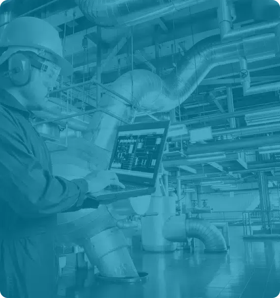 Industrial technician using laptop for equipment diagnostics in a processing plant—illustrating digital tools and reliability practices taught by Reliability Academy