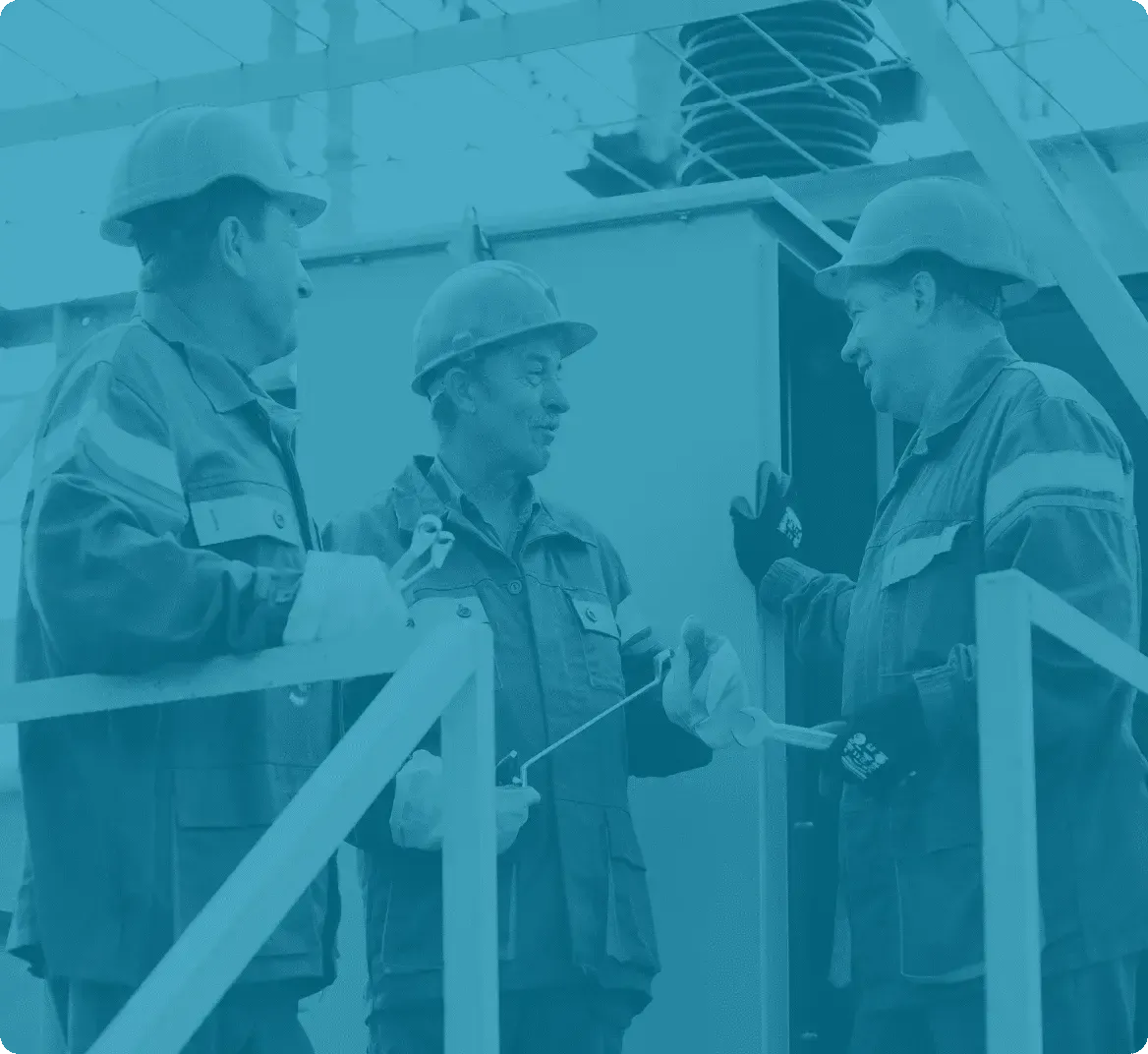 Three maintenance technicians in protective gear having a discussion at an industrial site, symbolising teamwork and communication in plant maintenance