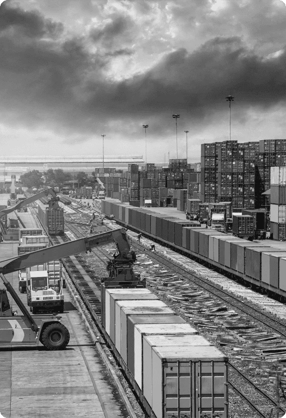 Rail freight terminal with container handlers and stacked cargo—representing logistics and transport sector in Reliability Academy’s maintenance training programmes